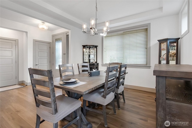 dining space featuring light wood-style flooring, baseboards, a chandelier, and a wealth of natural light