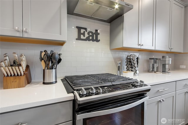 kitchen with tasteful backsplash, gas range, gray cabinets, light countertops, and under cabinet range hood