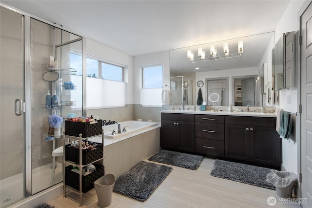 full bathroom with double vanity, a shower stall, a sink, and a bath