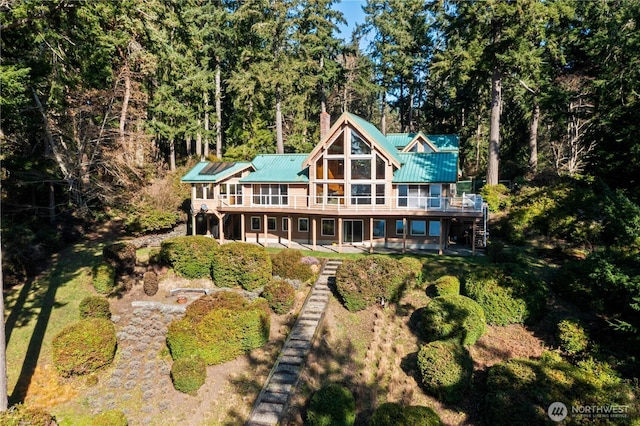 back of house with a deck, stairway, metal roof, and a chimney