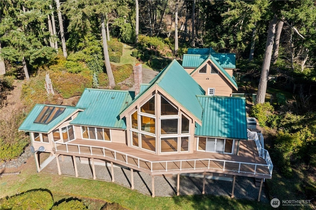 rear view of house featuring stairway, metal roof, and a chimney