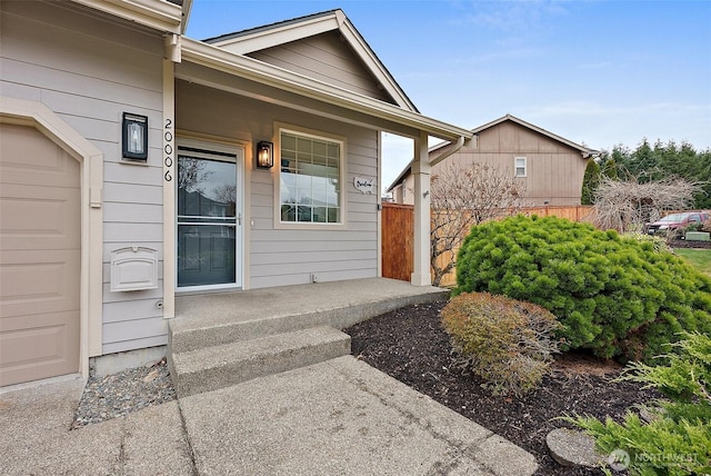 doorway to property with a garage and fence