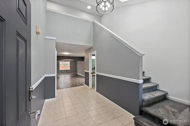 entryway featuring light tile patterned floors, a high ceiling, stairway, and baseboards