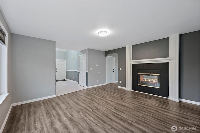 unfurnished living room with a fireplace, wood finished floors, and baseboards