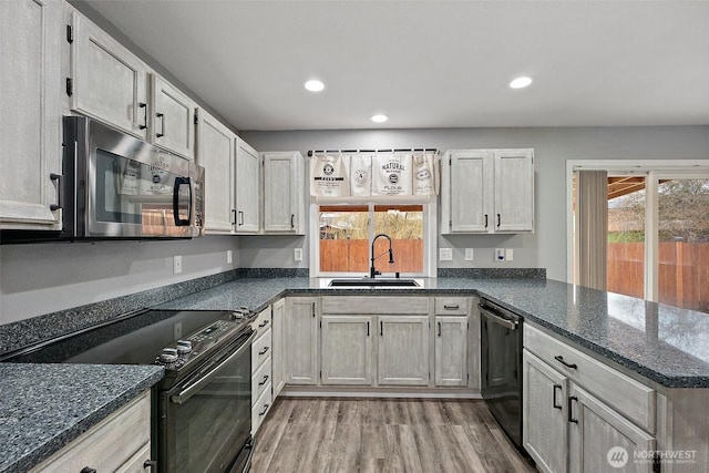 kitchen with dishwashing machine, a peninsula, a sink, black electric range oven, and stainless steel microwave