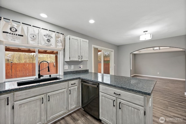 kitchen featuring dark wood-style floors, arched walkways, a sink, a peninsula, and dishwashing machine