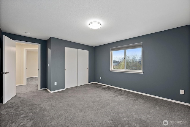 unfurnished bedroom with carpet floors, a closet, a textured ceiling, and baseboards