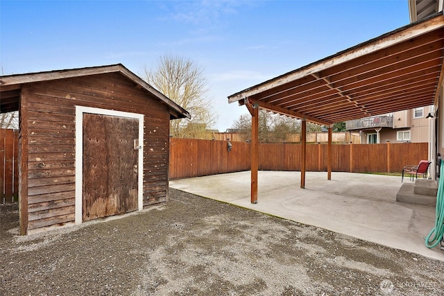 view of patio / terrace featuring a storage shed, fence, and an outdoor structure