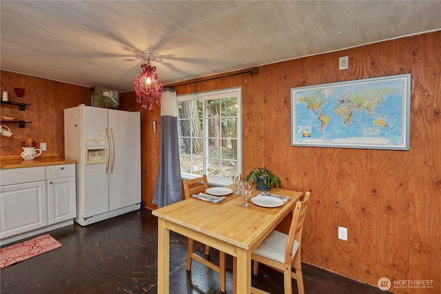 dining room featuring a notable chandelier and wooden walls