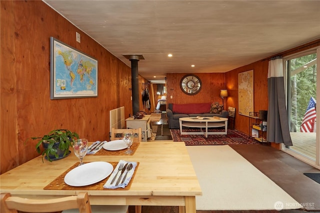 dining area featuring recessed lighting, wood walls, and a wood stove