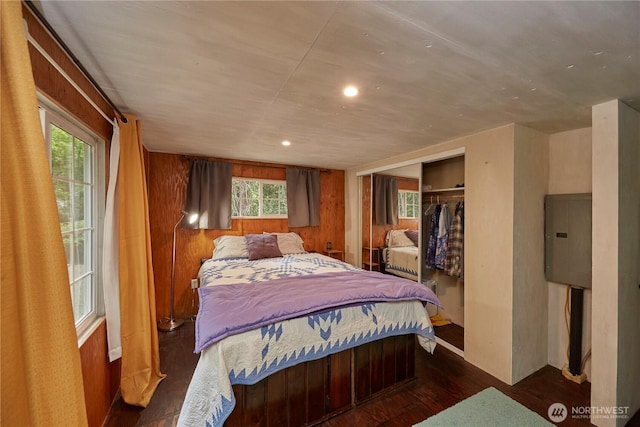 bedroom with a closet, wooden walls, and wood finished floors