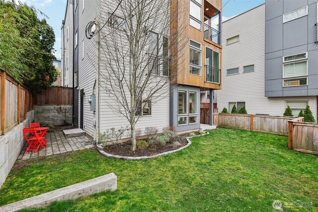 back of property featuring a fenced backyard, a lawn, and a patio