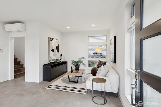 sitting room featuring an AC wall unit, recessed lighting, concrete floors, baseboards, and stairs