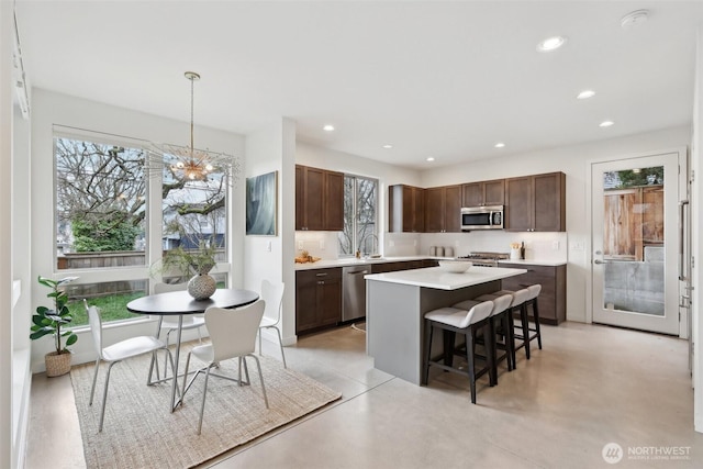 kitchen with a kitchen bar, a kitchen island, recessed lighting, appliances with stainless steel finishes, and light countertops