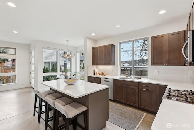 kitchen with tasteful backsplash, a breakfast bar area, light countertops, stainless steel appliances, and a sink