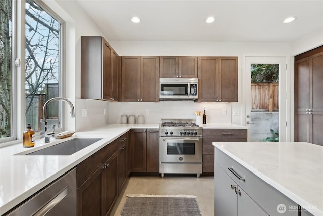 kitchen featuring a sink, backsplash, recessed lighting, stainless steel appliances, and light countertops