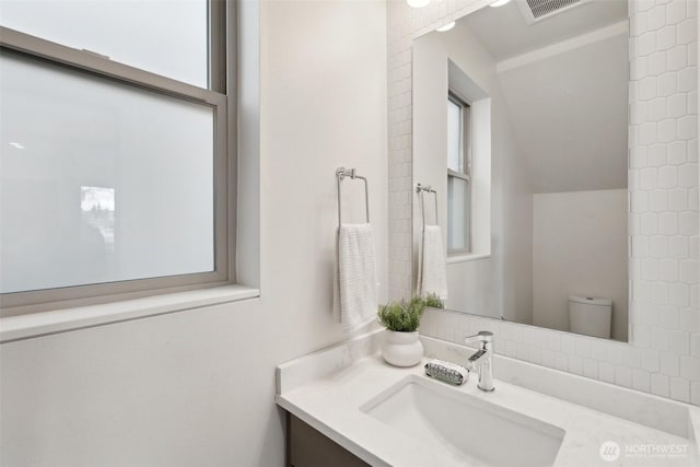 bathroom featuring vanity, vaulted ceiling, toilet, and visible vents