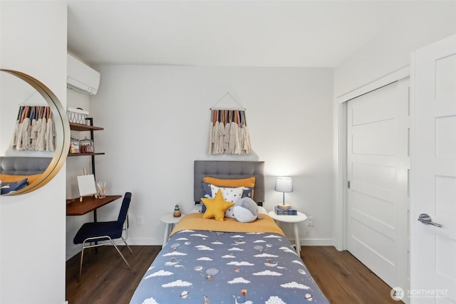 bedroom with baseboards, dark wood-type flooring, and a wall unit AC