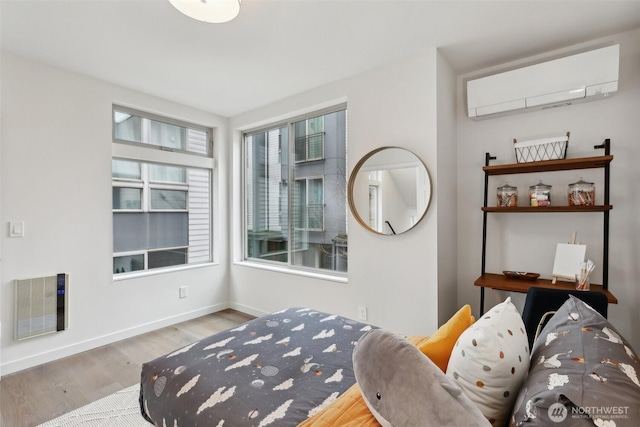 sitting room featuring an AC wall unit, wood finished floors, baseboards, and visible vents