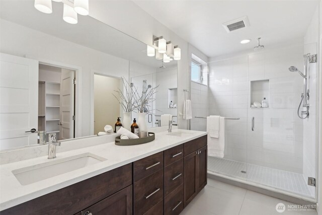 bathroom with a shower stall, double vanity, visible vents, and a sink