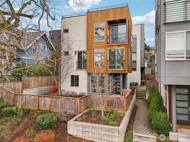 back of house featuring a vegetable garden and fence