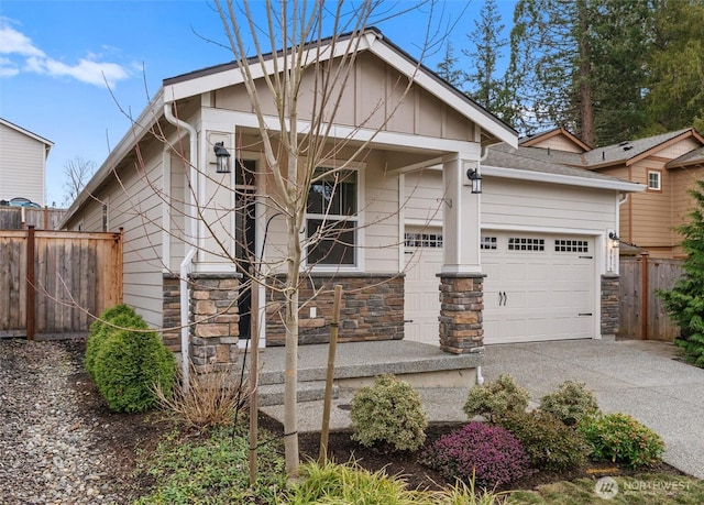 view of front of property with a garage, stone siding, driveway, and fence