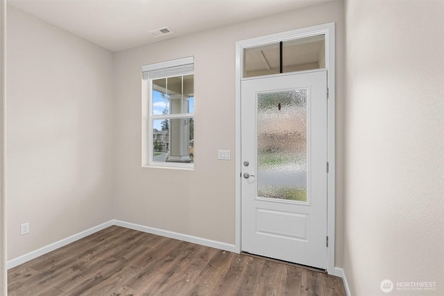 doorway to outside featuring visible vents, baseboards, a healthy amount of sunlight, and wood finished floors