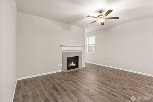 unfurnished living room with a fireplace, baseboards, and wood finished floors