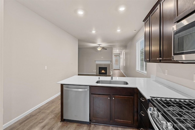 kitchen featuring a sink, dark brown cabinetry, appliances with stainless steel finishes, a peninsula, and ceiling fan