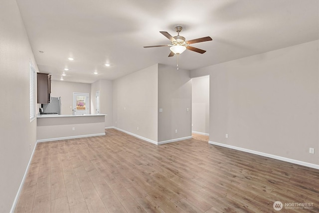 unfurnished living room with ceiling fan, baseboards, and light wood-style floors