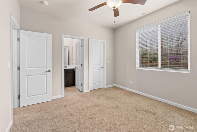 unfurnished bedroom with visible vents, baseboards, ensuite bath, ceiling fan, and light colored carpet