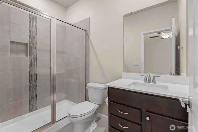 bathroom with vanity, toilet, a stall shower, and ceiling fan