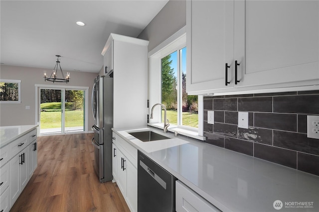 kitchen featuring plenty of natural light, white cabinetry, stainless steel appliances, and wood finished floors