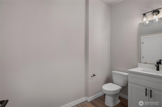 half bathroom with toilet, baseboards, wood finished floors, and vanity