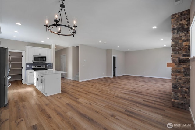 kitchen with tasteful backsplash, a kitchen island, stainless steel appliances, and light wood-style flooring