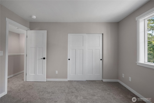 unfurnished bedroom with carpet, a closet, multiple windows, and baseboards