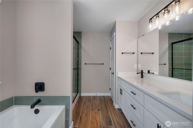 full bath featuring a stall shower, a garden tub, a sink, and wood finished floors