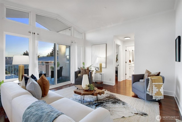 living area with vaulted ceiling, baseboards, and wood finished floors