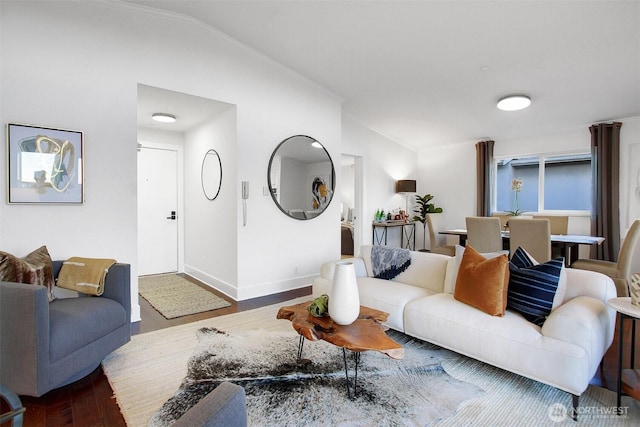 living room featuring ornamental molding, lofted ceiling, baseboards, and wood finished floors