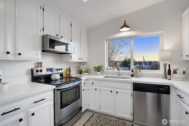 kitchen with light tile patterned floors, stainless steel appliances, light countertops, white cabinetry, and a sink