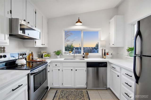 kitchen with light tile patterned floors, stainless steel appliances, a sink, white cabinetry, and light countertops