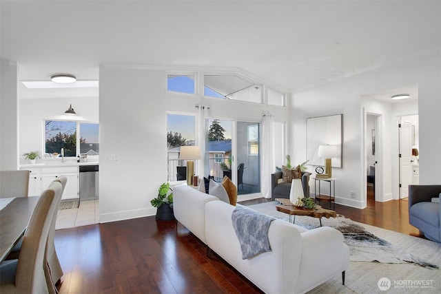 living area featuring vaulted ceiling, wood finished floors, and baseboards