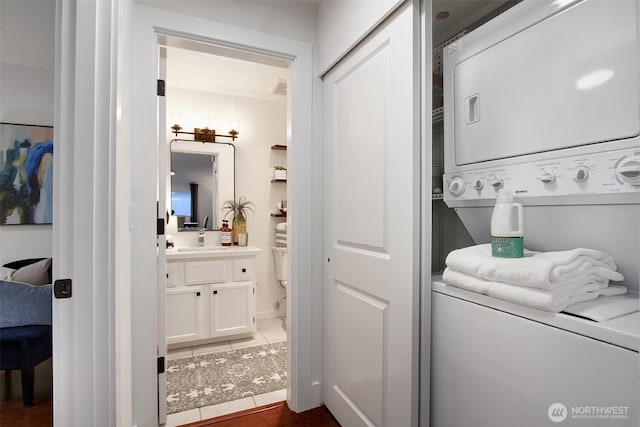 washroom with stacked washer / drying machine, laundry area, and tile patterned floors