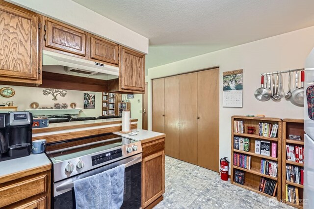 kitchen with light countertops, electric range, brown cabinets, and under cabinet range hood