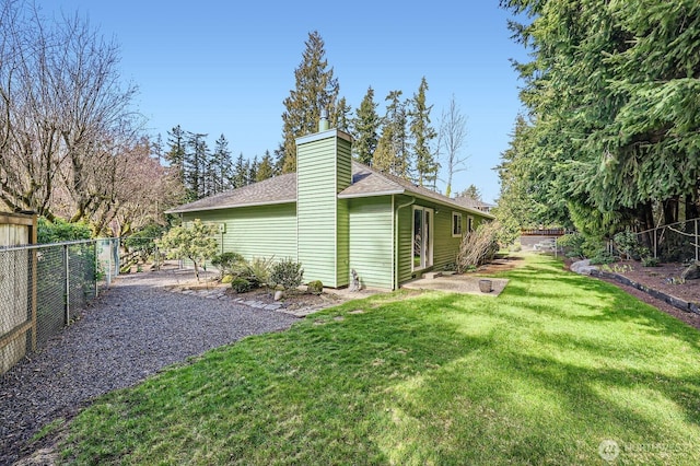 exterior space with a yard, a fenced backyard, roof with shingles, and a chimney