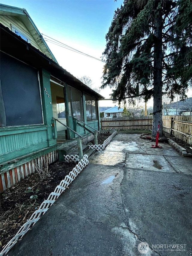 view of side of home with a patio area, a sunroom, and fence