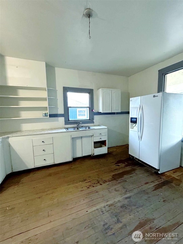 kitchen featuring dark wood-style flooring, white cabinetry, white refrigerator with ice dispenser, and a sink