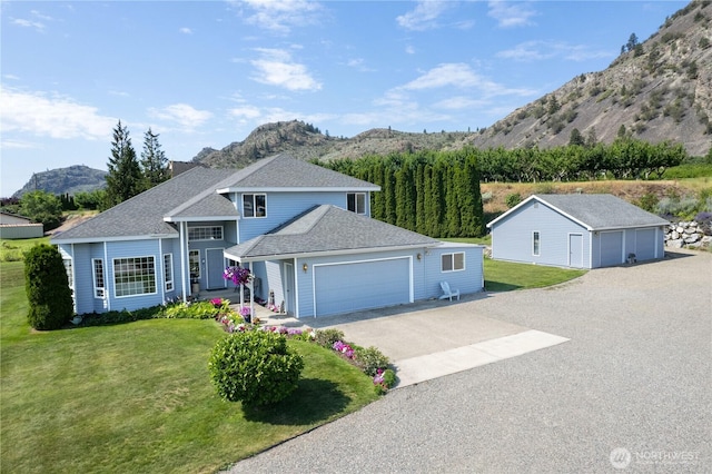 traditional-style home with a mountain view, driveway, a front yard, and a shingled roof