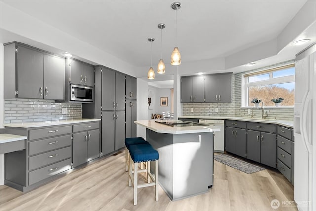 kitchen featuring white appliances, light wood-style flooring, gray cabinetry, and a sink