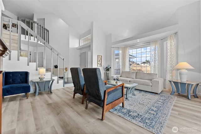 living room with stairway, a towering ceiling, and wood finished floors